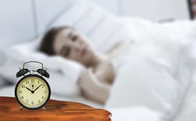  en kvinna som sover med en väckarklocka bredvid sin säng