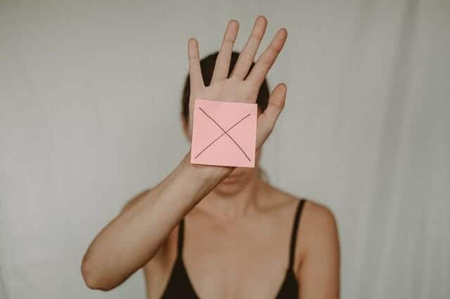  en ledsen kvinna håller en kartong med ett x framför sig