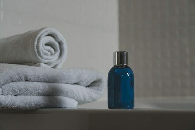  blå flaska med schampo, handdukar bredvid den