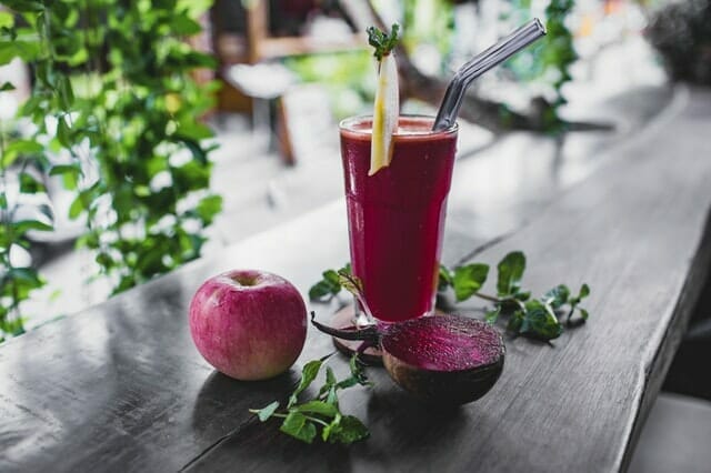  Rödbetsjuice i ett glas, bredvid ett äpple och en rödbeta.