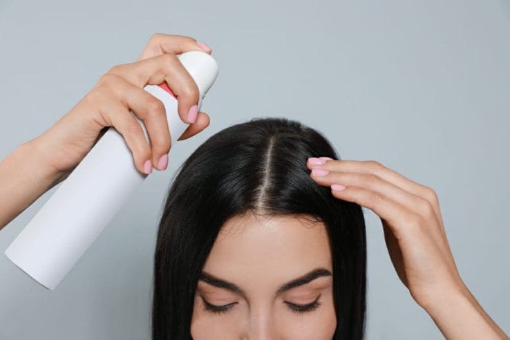  en kvinna använder torrschampo i sitt hår