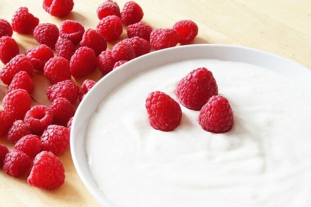  yoghurt i en skål, bredvid en hallon.
