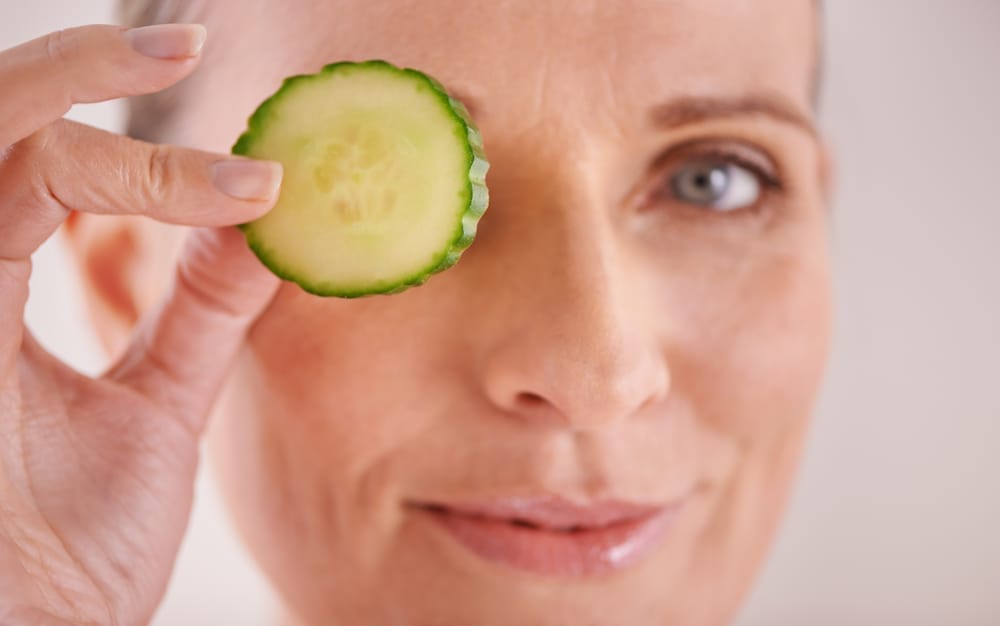  En kvinna håller en gurkskiva mot ögat