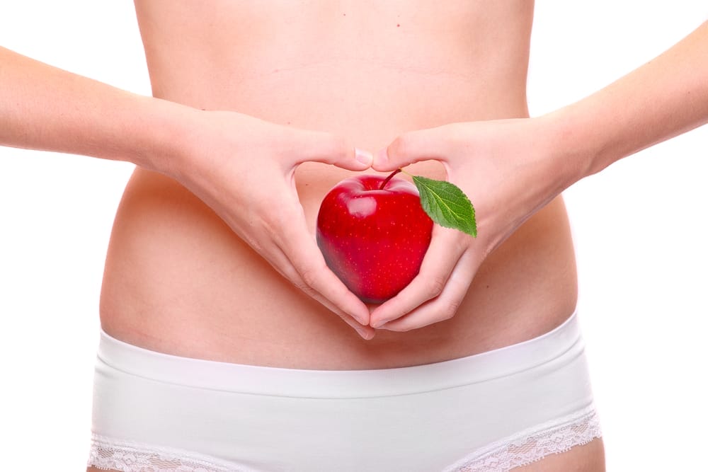  En kvinna håller ett äpple mot sin mage
